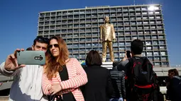 Warga berselfie dan mengabadikan patung emas raksasa PM Israel Benjamin Netanyahu di tengah-tengah Rabin Square, Tel Aviv, Selasa (6/12). (REUTERS / Baz Ratner)