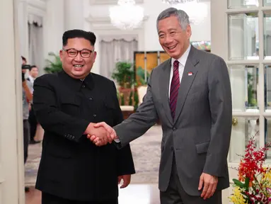 Perdana Menteri Singapura, Lee Hsien Loong bejabat tangan sambut kedatangan pemimpin Korea Utara Kim Jong-un di Istana Kepresidenan Singapura, Minggu (10/6). Kim Jong-un dan Donald Trump akan bertemu 12 Juni. (AFP Photo/HO/Kementerian Kominfo Singapura)