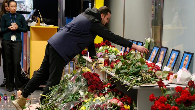 Kerabat salah satu kru pesawat 737-800 Ukraina yang jatuh di Iran, meletakkan bunga pada peringatan di bandara internasional Borispil, Kiev, Rabu (8/1/2020). Pesawat yang membawa 176 orang itu jatuh setelah lepas landas dari bandara utama Teheran dan menewaskan semua penumpang. (AP/Efrem Lukatsky)