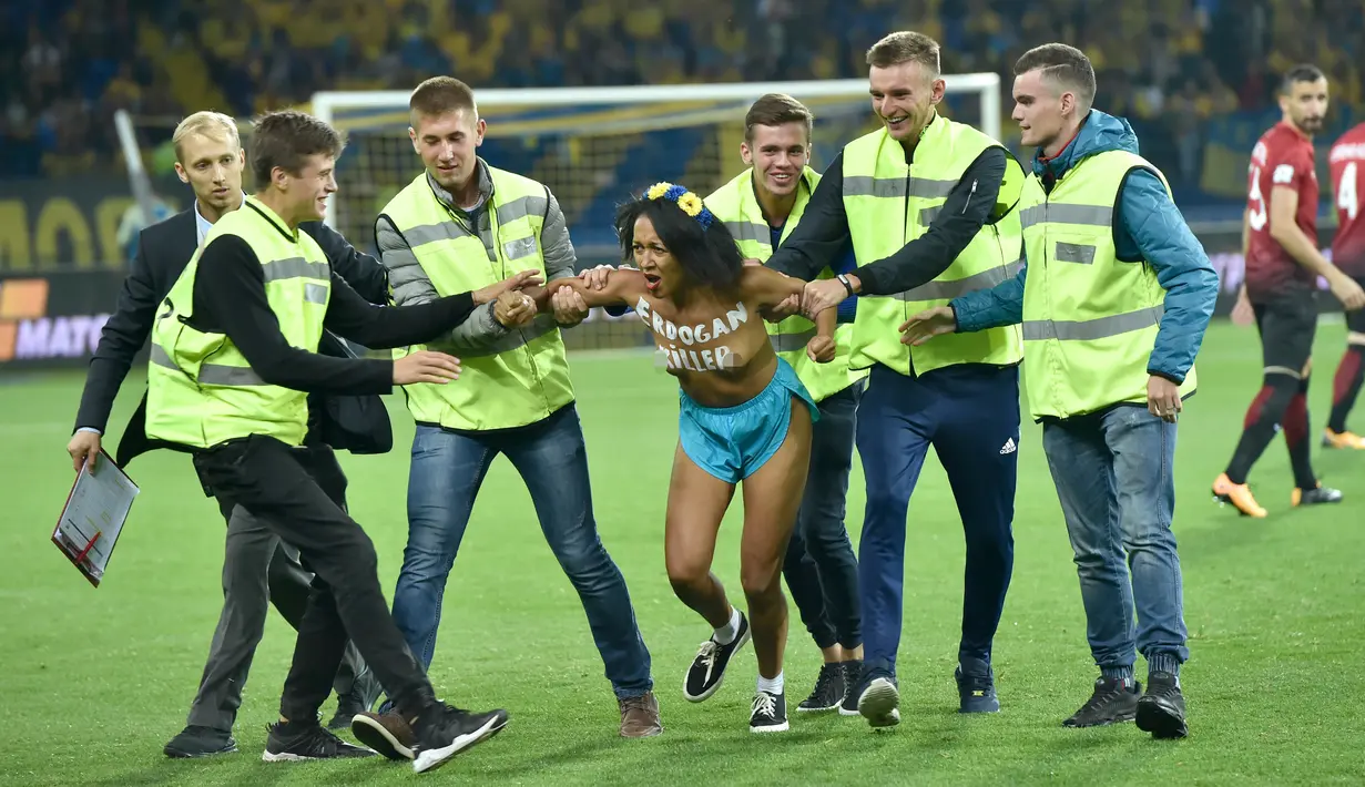 Petugas membawa wanita yang melakukan aksi protes di stadion di Kharkiv (2/9). Wanita itu memprotes rezim Erdogan yang dinilai telah membunuh kebebasan. (AFP Photo/Sergei Supinsky)