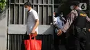 Belasan penyidik keluar secara beriringan. Beberapa diantaranya membawa barang-barang dari dalam rumah. (Liputan6.com/Herman Zakharia)