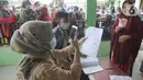 Petugas PT Pos Indonesia memotret wajah penerima Bantuan Sosial Tunai (BST) bulan Januari di halaman Masjid Jami Al-Hidayah RW 01 Bedahan, Depok, Selasa (16/2/2021). Sekitar 159.470 Keluarga Penerima Manfaat (KPM) di Kota Depok menerima BST yang disalurkan pada Februari ini (merdeka.com/Arie Basuki)