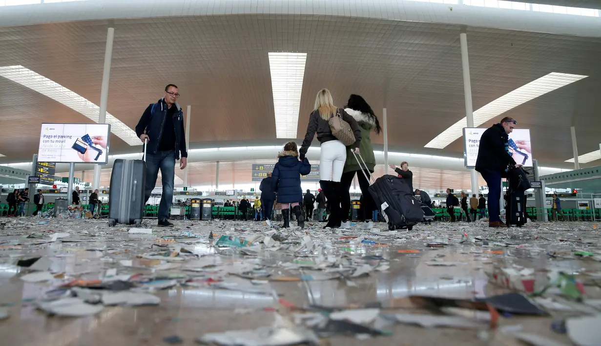Penumpang menarik koper melewati sampah yang berserakan di Bandara Barcelona, Spanyol, Kamis (1/12). Sampah-sampah yang berserakan tersebut sebagai bentuk aksi protes para petugas kebersihan untuk pemotongan anggaran 1,3 juta Euro. (REUTERS/Albert Gea)