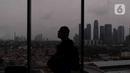 Seseorang melintas dekat jendela berlatar gedung bertingkat dan permukiman di kawasan Jakarta, Senin (17/1/2022). Bank Dunia memproyeksikan pertumbuhan ekonomi Indonesia pada tahun 2022 mencapai 5,2 persen. (Liputan6.com/Angga Yuniar)