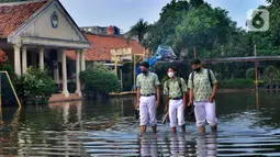 Siswa berjalan melewati banjir yang menggenangi halaman  sekolah di SMAN 4 Tangsel, Pondok Ranji, Tangerang Selatan, Banten, Selasa (14/6/2022). Tiga  pekan lebih banjir merendam lapangan sekolah itu dikarenakan tertutupnya saluran air oleh sampah yang berasal dari tempat pembuangan sampah (TPS) ilegal. (merdeka.com/Arie Basuki)