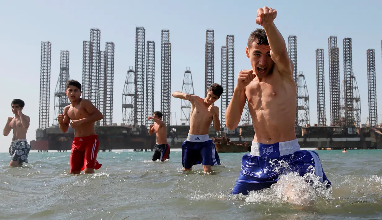 Anak-anak yang tergabung dalam sekolah kickboxing sedang berlatih di tepi Laut Kaspia dekat dengan bekas tempat pengeboran minyak era Soviet di kota Baku, Azerbaijan, Sabtu (27/6). (AP Photo/Dmitry Lovetsky)