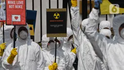 Aktivis Greenpeace saat menggelar aksi damai kreatif menolak energi nuklir di depan Gedung DPR, Jakarta, Jumat (13/3/2020). Aksi ini bagian dari peringatan sembilan tahun bencana Fukushima. (Liputan6.com/Johan Tallo)