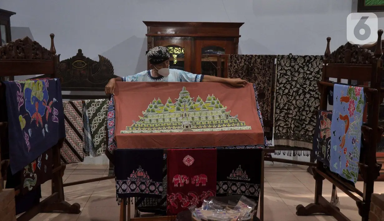 Adiwinarto menunjukkan karya batik di galeri Lumbini di Dusun Tingal, Desa Wanurejo, Kecamatan Borobudur, Kabupaten Magelang, Jawa Tengah, Selasa (17/5/2022). Batik tulis Lumbini menawarkan motif yang terinspirasi dari relief Candi Borobudur, pinisi, liman kembar, mandala, dan daun bodi. (merdeka.com/Iqbal S. Nugroho)