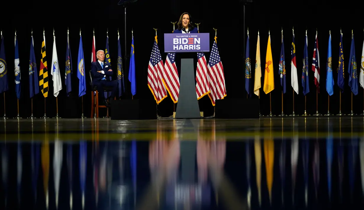 Calon Presiden Partai Demokrat, Joe Biden mendengarkan pasangannya, Kamala Harris selama acara kampanye di Alexis Dupont High School di Wilmington, Delaware, Rabu (12/8/2020).  Acara itu menjadi penampilan perdana keduanya di depan publik sebagai pasangan capres-cawapres. (AP Photo/Carolyn Kaster)