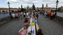 Warga menggelar makan malam di atas meja sepanjang 500 meter di jembatan bersejarah Charles Bridge di Praha, Republik Ceko, Selasa (30/6/2020). Kegiatan itu merupakan perpisahan simbolis yang digelar untuk menandai akhir dari masa krisis virus corona Covid-19 di negara tersebut (AP/Petr David Josek)