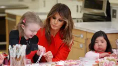 Istri Presiden AS, Melania Trump membantu seorang anak menghias kue saat berkunjung ke Children's Inn di National Institute of Health (14/2). Mengenakan jas merah, Melania bertukar kartu valentine dengan anak-anak. (AP Photo/Pablo Martinez Monsivais)
