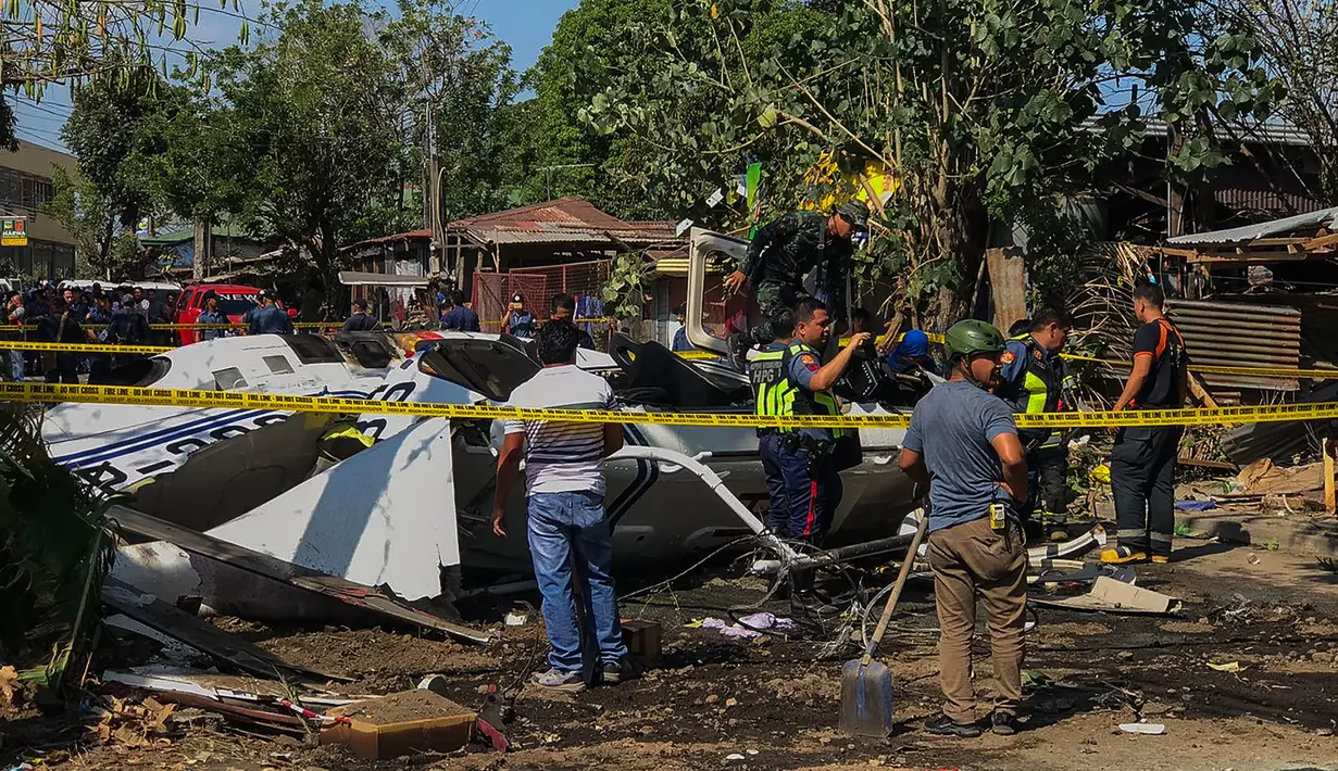 Penyelidik berdiri di dekat puing-puing Helikopter bell 429 yang membawa kepala polisi Filipina setelah jatuh di Kota San Pedro, selatan Manila, Kamis (5/3/2020). Tidak ada yang tewas dalam kejadian tersebut, dan semua penumpang dibawa ke rumah sakit untuk menjalani perawatan. (AFP)