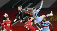 Kiper Manchester United, Dean Henderson, berusaha menghalau bola saat melwan West Ham United pada laga Liga Inggris di Stadion Old Trafford, Minggu (15/3/2021). Setan Merah menang dengan skor 1-0. (AP/Clive Brunskill,Pool)