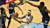 Guard Utah Jazz, Jordan Clarkson, berusaha menembak di antara pemain Memphis Grizzlies, Ja Morant dan Jaren Jackson Jr.pada paruh kedua pertandingan keempat babak play-off NBA, Selasa (1/6/2021) pagi WIB. (AP Photo/Brandon Dill)