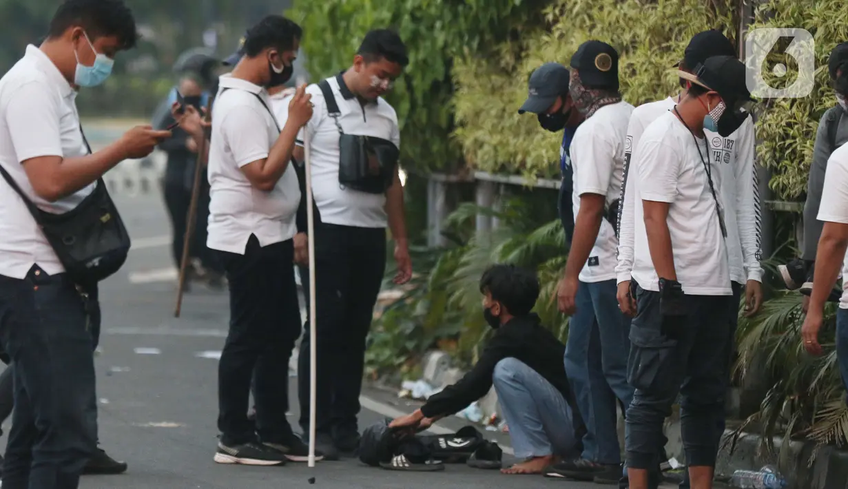 Polisi berpakaian kaus putih memeriksa seorang anak muda yang dicurigai terlibat kericuhan di kawasan Tugu Tani, Jakarta, Selasa (13/10/2020). Sejumlah pemuda diamankan polisi karena dicurigai terlibat kericuhan di kawasan Tugu Tani. (Liputan6.com/Helmi Fithriansyah)