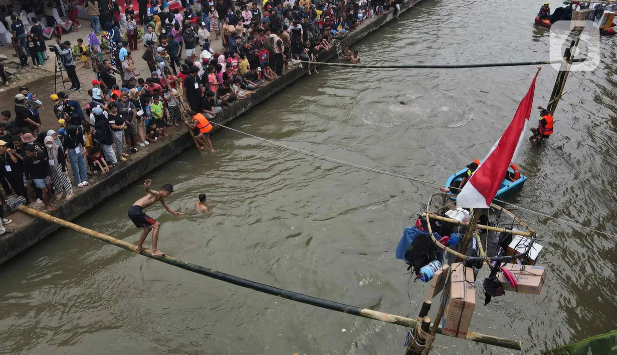 Seorang warga mengikuti perlombaan jalan di atas bambu di aliran Kalimalang, Jakarta Timur, Sabtu (27/8/2022). Perlombaan di Kalimalang yang diselenggarakan kembali setelah dua tahun berhenti akibat pandemi covid-19 ini untuk memeriahkan peringatan HUT ke-77 Kemerdekaan RI. (Liputan6.com/Herman Zakharia)