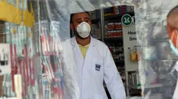 Pegawai melayani pembeli dari balik lapisan plastik untuk mengurangi kontak fisik di sebuah apotek di Baghdad, Irak, Selasa (14/4/2020). Kedispilinan masyarakat dalam menjaga jarak fisik atau physical distancing sangat berpengaruh dalam langkah meredam penyebaran virus corona COVID-19. (Xinhua)