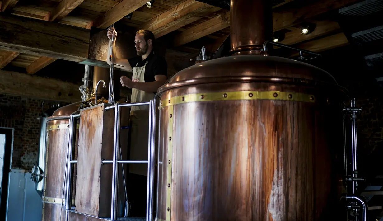 Manajer Waterloo Microdistillery, Edward Martin bekerja di Mont-Saint-Jean Farm, Waterloo, Belgia, Selasa (7/4/2020). Di tengah pandemi virus corona COVID-19, pabrik sopi dan wiski Mont-Saint-Jean Farm beralih memproduksi alkohol medis. (Kenzo TRIBOUILLARD/AFP)
