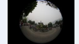 Para pebalap sepeda saat melewati sebuah tugu di kota Sawahlunto dalam Etape 4 Tour de Singkarak 2015, Selasa (6/10/2015). (Bola.com/Arief Bagus)
