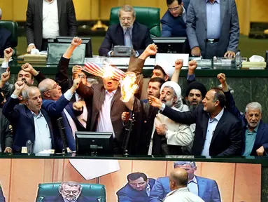 Anggota parlemen Iran membakar dua lembar kertas bergambar bendera AS, Teheran, Iran, Rabu (9/5). Aksi itu dilakukan sebagai kecaman atas kebijakan Presiden AS Donald Trump yang keluar dari kesepakatan nuklir Iran. (AP Photo)