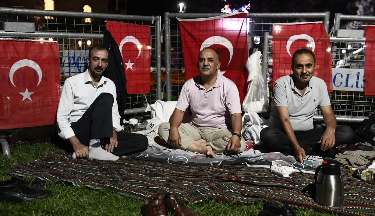 Orang-orang duduk di luar Hagia Sophia era Bizantium, di distrik bersejarah Sultanahmet di Istanbul, Kamis, 23 Juli 2020, sehari sebelum sholat Muslim pertama di monumen tengara dalam 86 tahun setelah konversi kembali menjadi masjid. (AP Photo/Omer Kuscu)