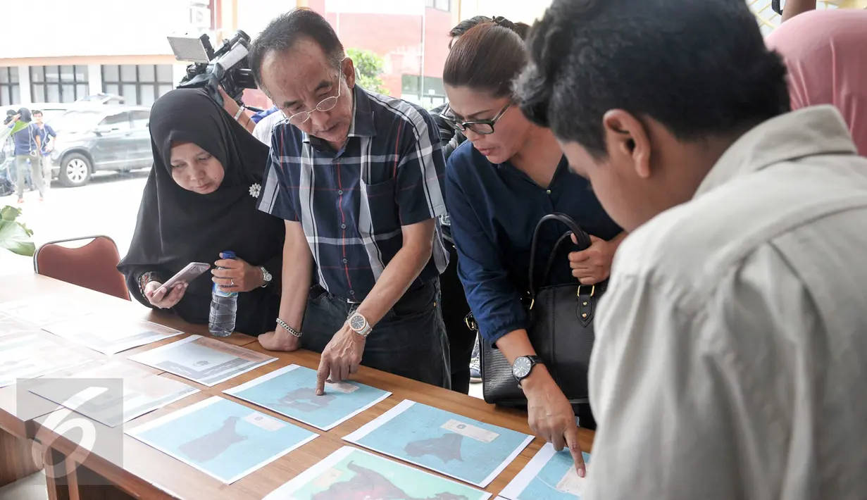 Keluarga korban melihat foto properti dari jenazah korban KM Zahro yang belum teridenfikasi di RS Polri, Jakarta, Selasa (3/1). Penempelan foto hasil postmortem bertujuan untuk membantu pengenalan oleh pihak keluarga. (Liputan6.com/Yoppy Renato)