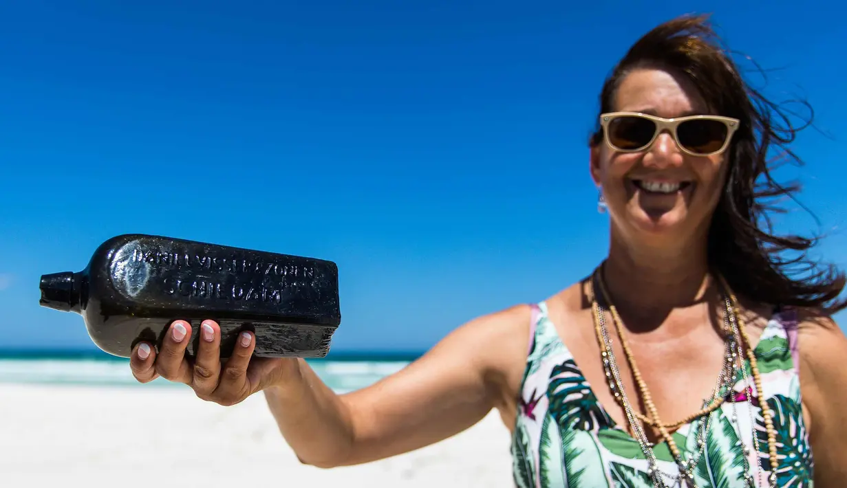 Tonya Illman memegang sebuah botol yang berisi pesan berusia hampir 132 tahun, yang dia temukan di dekat Pulau Wedge, sekitar 160 kilometer di utara Perth (7/3). Pesan tertua di dunia ini ditemukan pada bulan Januari. (AFP Photo/Kym Illman)
