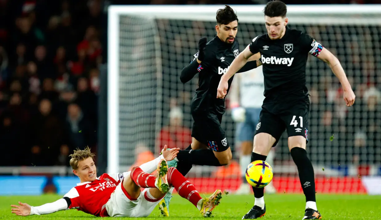 Pemain Arsenal Martin Odegaard (kiri) berduel memperebutkan bola dengan pemain West Ham United Lucas Paqueta (kiri) dan Declan Rice pada pertandingan sepak bola Liga Inggris di Emirates Stadium, London, Inggris, 26 Desember 2022. Arsenal mengalahkan West Ham United dengan skor 3-1. (AP Photo/David Cliff)