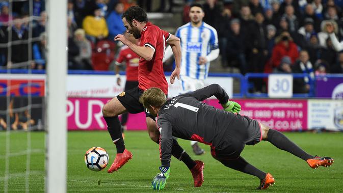 Gelandang Manchester United, Juan Mata berusaha dihadang oleh kiper Huddersfield Town, Jonas Lossl pada pertandingan putaran kelima Piala FA di John Smith's Stadium, Minggu (18/2). MU melaju ke perempatfinal Piala FA setelah menang 2-0. (Oli SCARFF/AFP)