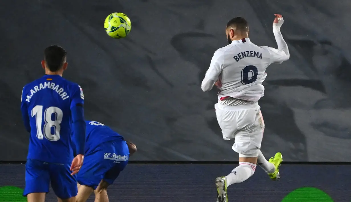 Striker Real Madrid, Karim Benzema (kanan) melepaskan sundulan ke gawang Getafe yang berbuah gol pertama timnya dalam laga lanjutan Liga Spanyol 2020/21 pekan ke-22 di Alfredo di Stefano Stadium, Selasa (9/2/2021). Real Madrid menang 2-0 atas Getafe. (AFP/Gabriel Bouys)