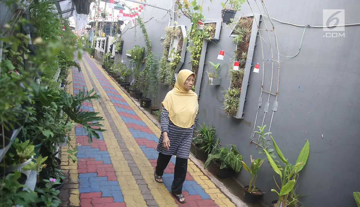 Warga melintas di salah satu gang kampung hijau di kawasan Malakasari, Jakarta, Sabtu (15/9). Tingginya kesadaran masyarakat akan pentingnya tumbuhan membuat kawasan tersebut terlihat asri dan dipenuhi berbagai tanaman. (Liputan6.com/Immanuel Antonius)