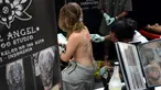 Seorang wanita saat dibuatkan tato dibagian punggung oleh seniman dalam acara Bali Tattoo Expo 2017 di pulau resor Indonesia, Denpasar, Bali (12/5). Acara ini digelar selama 3 hari, mulai (12/5/2017) sampai (14/5/2017). (AFP Photo/Sonny Tumbelaka)