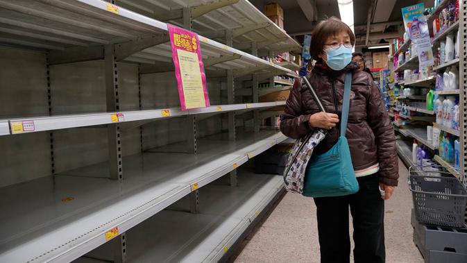 Warga mengenakan masker berjalan melewati rak kertas tisu yang kosong di sebuah supermarket di Hong Kong, Kamis (6/2/2020). Warga Hong Kong yang sedang waspada virus corona dilanda kepanikan setelah muncul gosip bahwa China akan berhenti memproduksi kertas toilet selama dua pekan. (AP/Vincent Yu)