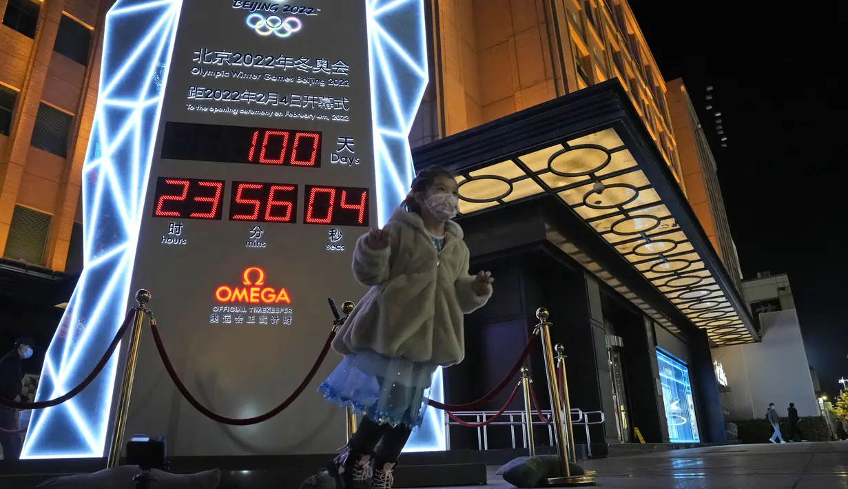 Seorang anak kecil berdiri di dekat jam hitung mundur 100 hari menuju pembukaan Olimpiade Musim Dingin Beijing 2022, di Beijing, China, Selasa (26/10/2021). Olimpiade Musim Dingin Beijing 2022 akan berlangsung 4 hingga 20 Februari. (AP Photo/Ng Han Guan)