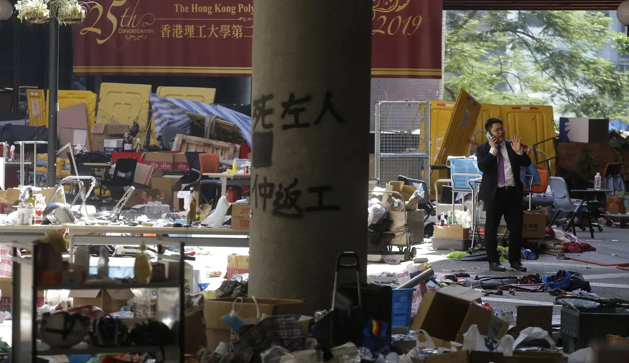 Seorang pria dikelilingi oleh sampah setelah protes besar-besaran di kampus Universitas Politeknik di Hong Kong (22/11/2019).  Enam pemrotes bertopeng dari universitas menyerah pada Jumat pagi, sehingga jumlahnya sekitar 30 yang telah keluar. (AP Photo/Achmad Ibrahim)