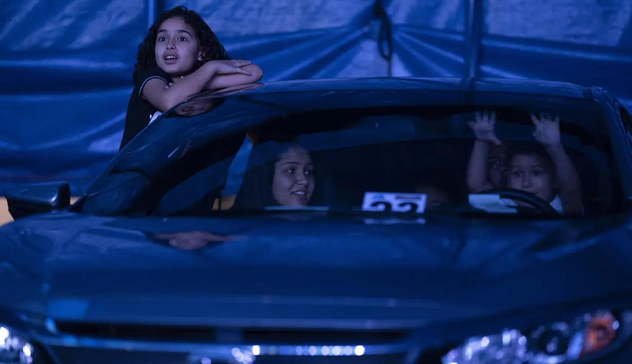 Anak-anak menonton pertunjukan Estoril Circus berformat drive-in di Itaguai, Rio de Janeiro, Brasil, Sabtu (18/7/2020). Pertunjukan yang berlangsung di tengah pandemi tersebut mengikuti langkah-langkah untuk mengekang penyebaran COVID-19. (AP Photo/Leo Correa)