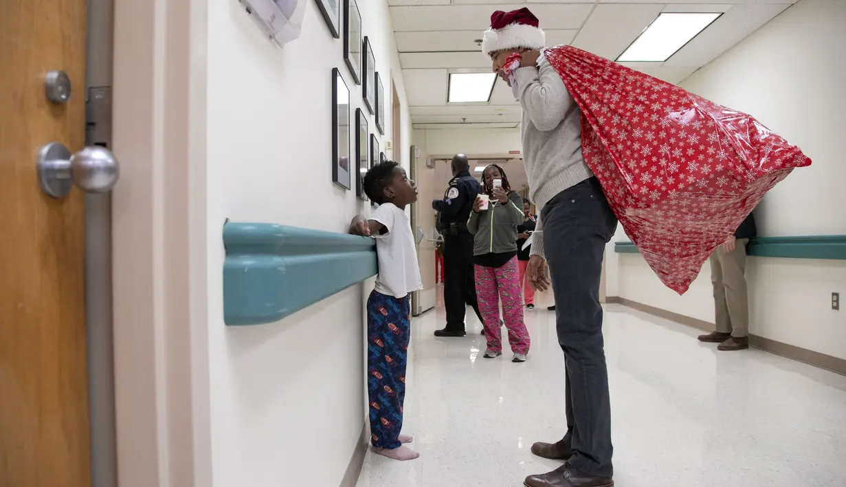 Mantan Presiden AS, Barack Obama mengobrol dengan seorang pasien anak di Children's National Medical Center , Washington, Rabu (19/12). Obama mengunjungi anak-anak yang sedang menjalani perawatan di sana untuk membagikan kado Natal. (Chuck Kennedy / AFP)