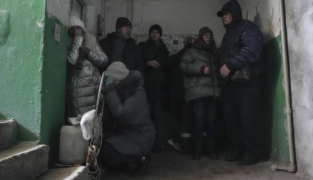 Orang-orang berlindung dari penembakan di dalam pintu masuk gedung apartemen di Mariupol, Ukraina, Minggu, 13 Maret 2022. Pada 24 Februari 2022, Rusia melancarkan invasi berskala besar ke Ukraina, salah satu negara tetangganya di sebelah barat daya. (AP Photo/Evgeniy Maloletka)