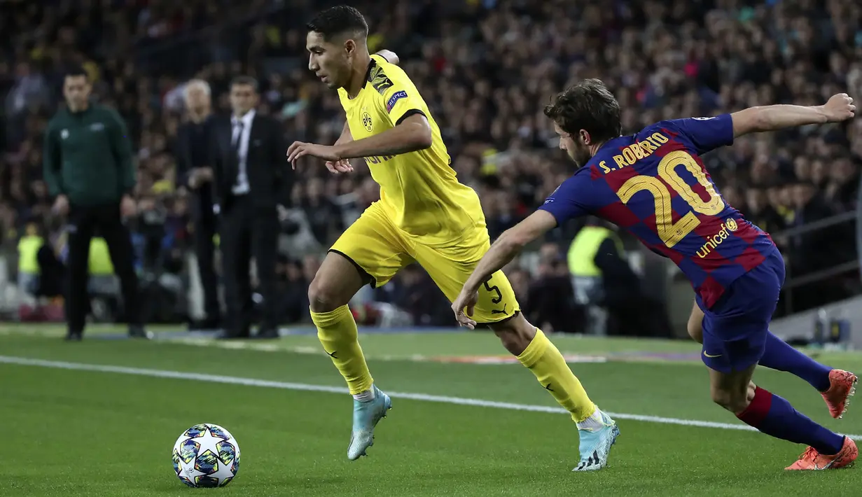 Gelandang Borrusia Dortmund, Achraf Hakimi berusaha melewati bek Barcelona, Sergi Roberto pada pertandingan Grup F Liga Champions di stadion Camp Nou, Spanyol (27/11/2019). Barcelona menang 3-1 atas Dortmund. (AP Photo/Emilio Morenatti)