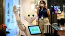 Seorang perempuan mengambil gambar robot 5G yang menyambut pengunjung di pusat perbelanjaan di Bangkok, Thailand, Kamis (4/6/2020). Thailand menggunakan teknologi di garis depan untuk menjaga ruang publik dari penyebaran pandemi corona Covid-19. (Mladen ANTONOV / AFP)