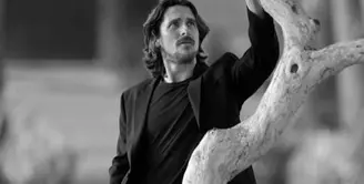 Christian Bale sedang ramai dibicarakan, karena penampilannya di film Thor: Love and Thunder. Salah satu gaya khasnya adalah tampil dengan rambut gondrong, lengkap dengan kumis dan jenggotnya, seperti dalam foto ini. Foto hitam putih yang menampakkan dirinya berpose di dekat sebuah pohon mengenakan kaus yang ditumpuk dengan blazer, dipadu celana jeans, lengkap dengan beltnya. Foto: Instagram.