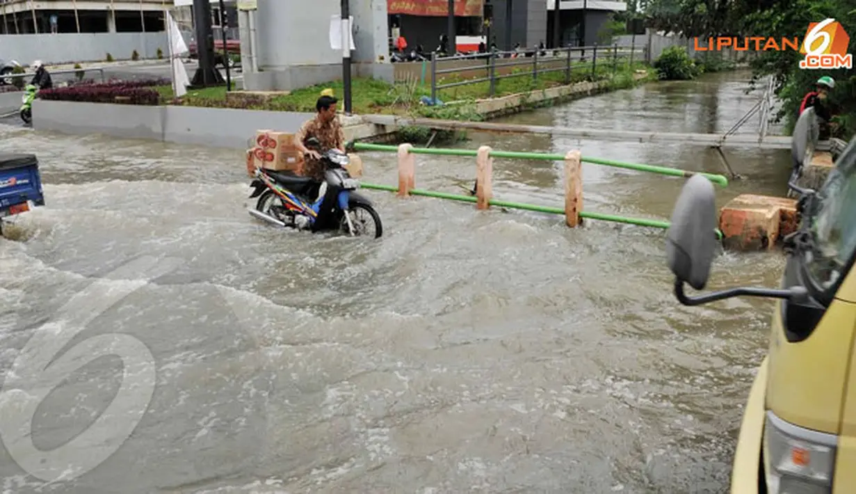 Lantaran nekat menerjang genangan air, pengendara sepeda motor terpaksa menuntun kendaraannya karena mogok (Liputan6.com/Andrian M Tunay)