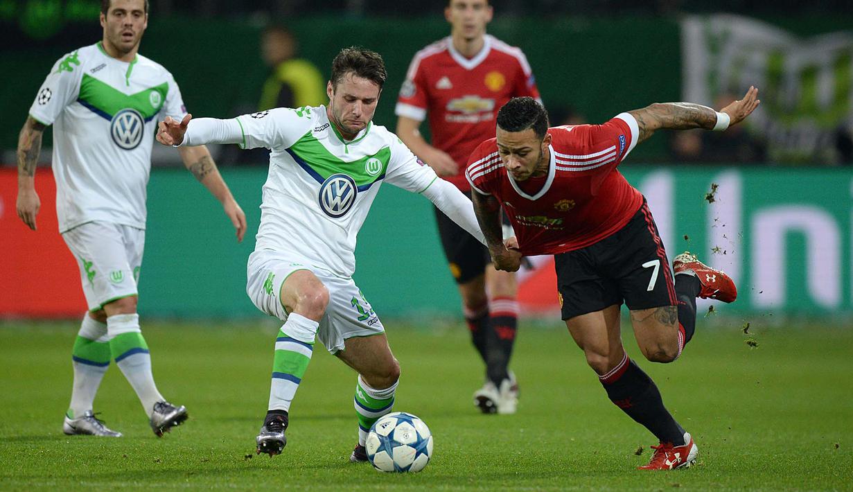 Pemain Wolfsburg, Christian Traesch (tengah) berebut bola dengan pemain Manchester United, Memphis Depay  pada lanjutan liga Champions di Stadion VfL Wolfsburg Arena, Rabu (9/12/2015) dini hari WIB. (AFP Photo/Julian Stratenschulte)