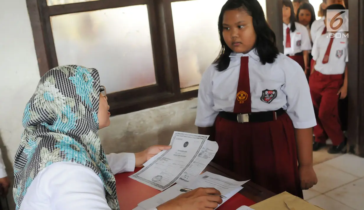 Petugas mencocokan data siswa saat membuat Kartu Identitas Anak (KIA) di SD Negeri 01 Sawah Baru, Ciputat, Jumat (27/4). KIA ini bermanfaat sebagai bentuk pemenuhan hak anak dan dokumen kependudukan. (Merdeka.com/Arie Basuki)