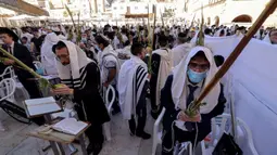Umat Yahudi memanjatkan doa saat memperingati Hari Raya Sukkot di Tembok Barat, Kota Tua Yerusalem, 22 September 2021. Sukkot adalah hari raya untuk memperingati eksodus bangsa Israel dari Mesir sekitar 3200 tahun yang lalu. (Emmanuel DUNAND/AFP)