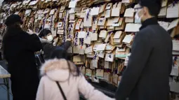 Seorang gadis menggantung papan "ema" dengan keinginannya tertulis di atasnya di kuil Yushima Tenmangu di Tokyo pada Hari Tahun Baru, Jumat (1/1/2021). Papan tersebut biasanya ditulisi dengan doa atau harapan penulisnya agar lebih cepat dikabulkan oleh dewa.  (AP Photo/Hiro Komae)