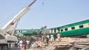 Alat berat dikerahkan untuk mengevakuasi gerbong dalam kecelakaan dua kereta di distrik Rahim Yar Khan, Pakistan, Kamis (11/7/2019). Insiden ini menyebabkan setidaknya sembilan orang tewas dan lebih dari 60 lainnya luka-luka. (AP Photo/Waleed Saddique)