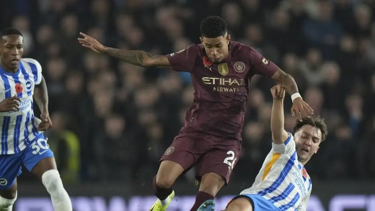 Duel Savinho dan Adam Webster dalam laga Brighton vs Manchester City di Premier League 2024/2025. (c) AP Photo/Alastair Grant