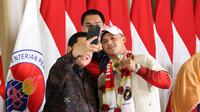 Rizki Juniansyah (kanan) berswafoto bersama Erick Thohir (depan kiri) dan Dito Ariotedjo saat penyambutan kedatangan kontingen Olimpiade di Bandara Internasional Soekarno-Hatta, Selasa (13/8/2024) malam WIB. (Bola.com/Abdul Aziz)