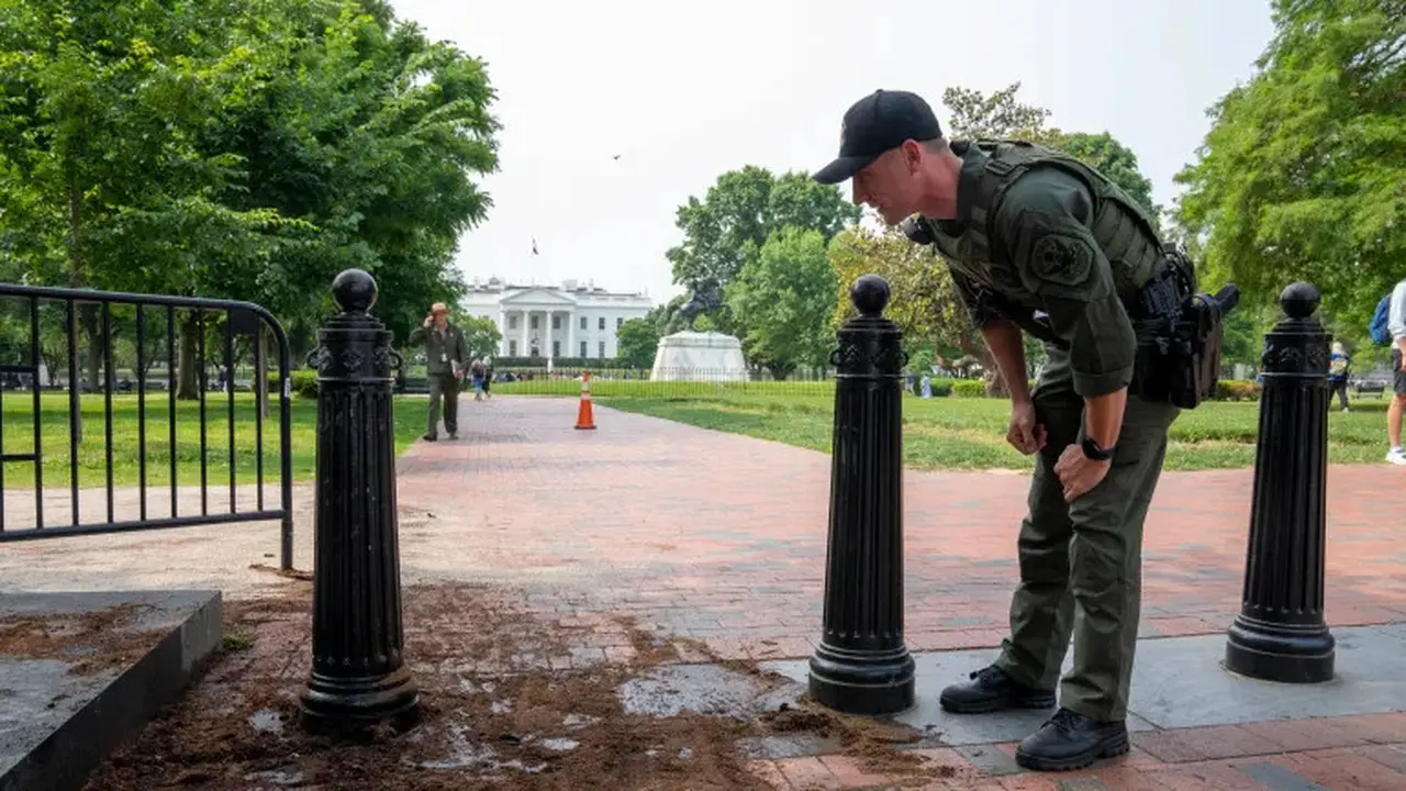 Seorang polisi taman AS memeriksa penghalang keamanan untuk kerusakan di taman Lafayette Square dekat Gedung Putih. [Alex Brandon/AP]